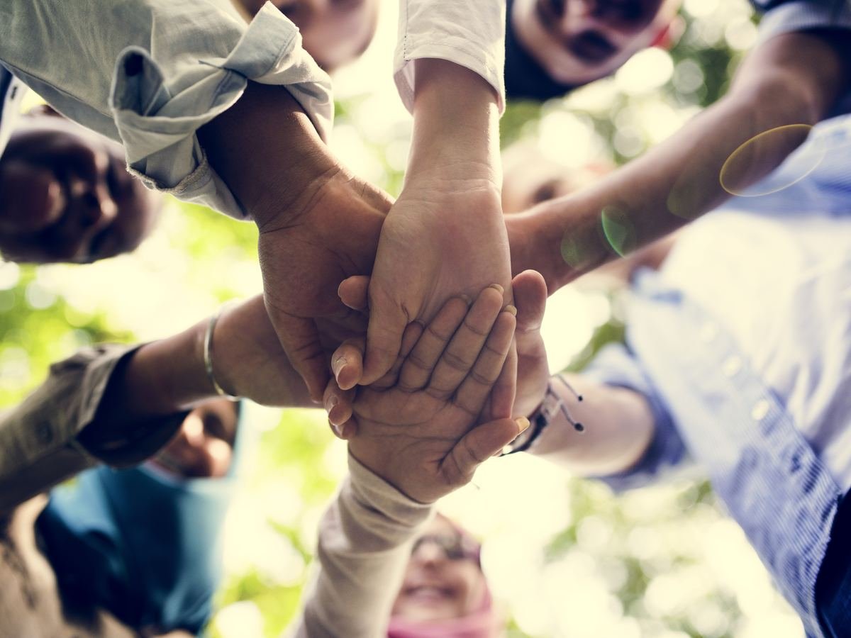 Close-up of hands joined together outdoors, symbolising solidarity